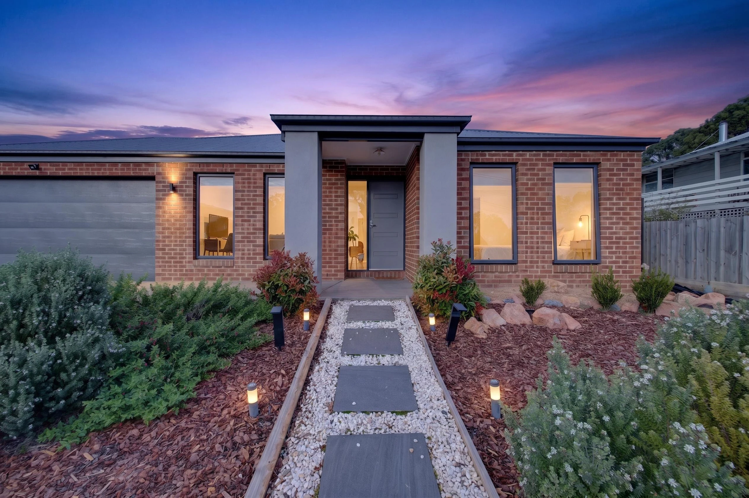 Front exterior view of Captains Edge holiday home at sunset with warm evening light highlighting the entrance and modern design.
