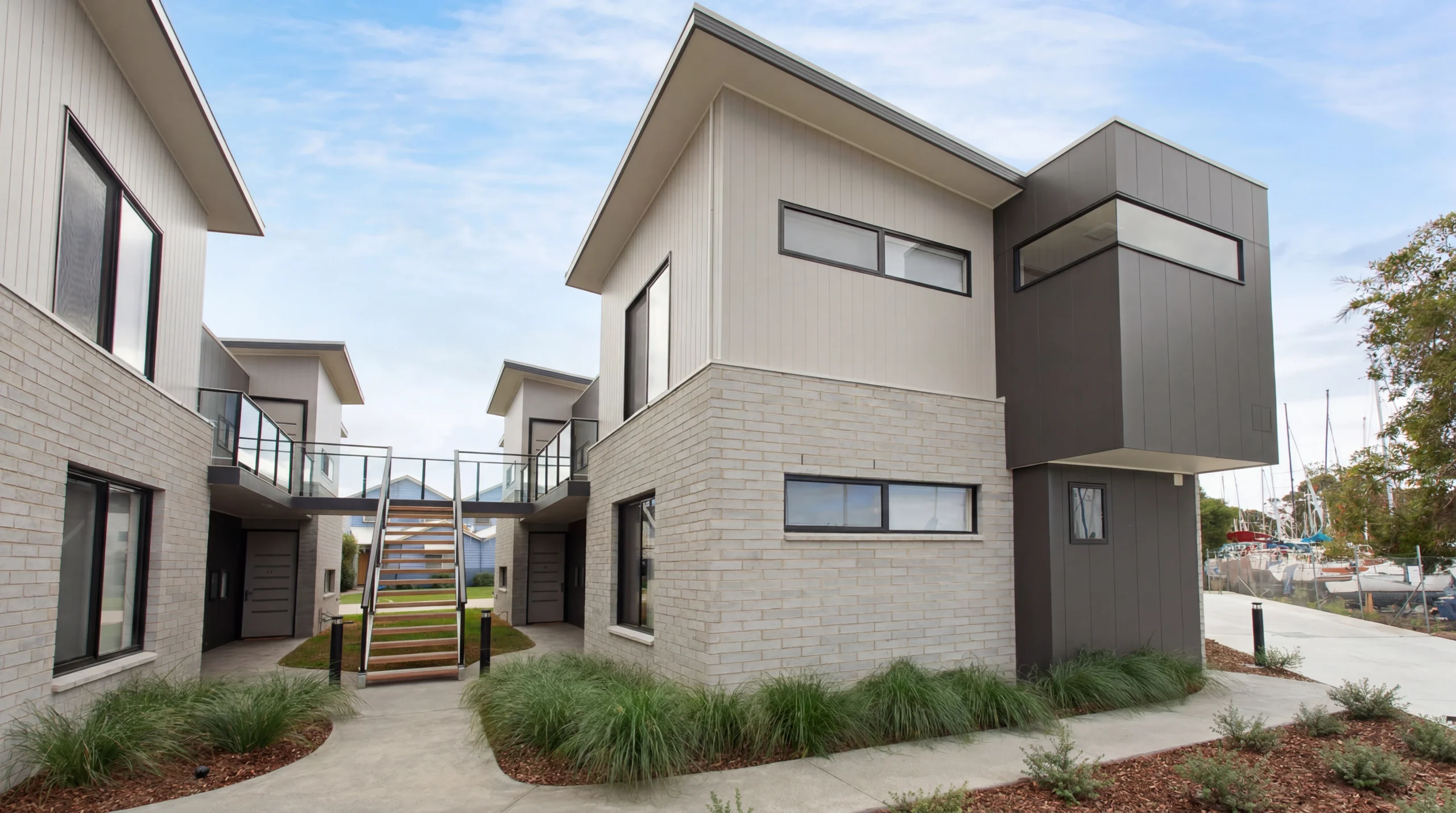 Exterior view of ground floor apartment building in Gippsland seen from the on-site carpark, featuring private entrances and landscaped garden surrounds.