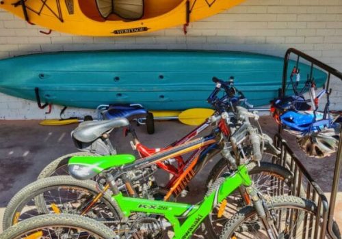 A variety of hiring equipment for exploring Gippsland Lakes, including a yellow kayak mounted on the wall, a blue canoe, and several bicycle