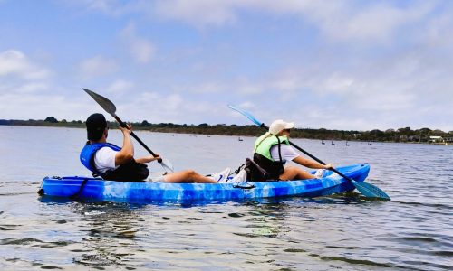Adult couple kayaking on Gippsland Lakes in a double kayak available for hire